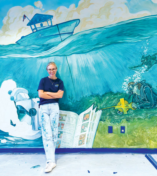 Student artist working on the University Library mural