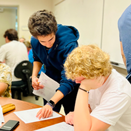A brunet LA in a blue hoodie working with a blond student in a white shirt