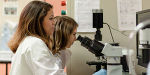 Photo of female students looking through microscope