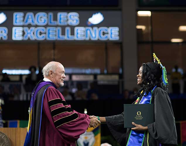 Photo of President Martin shaking hands with graduating student