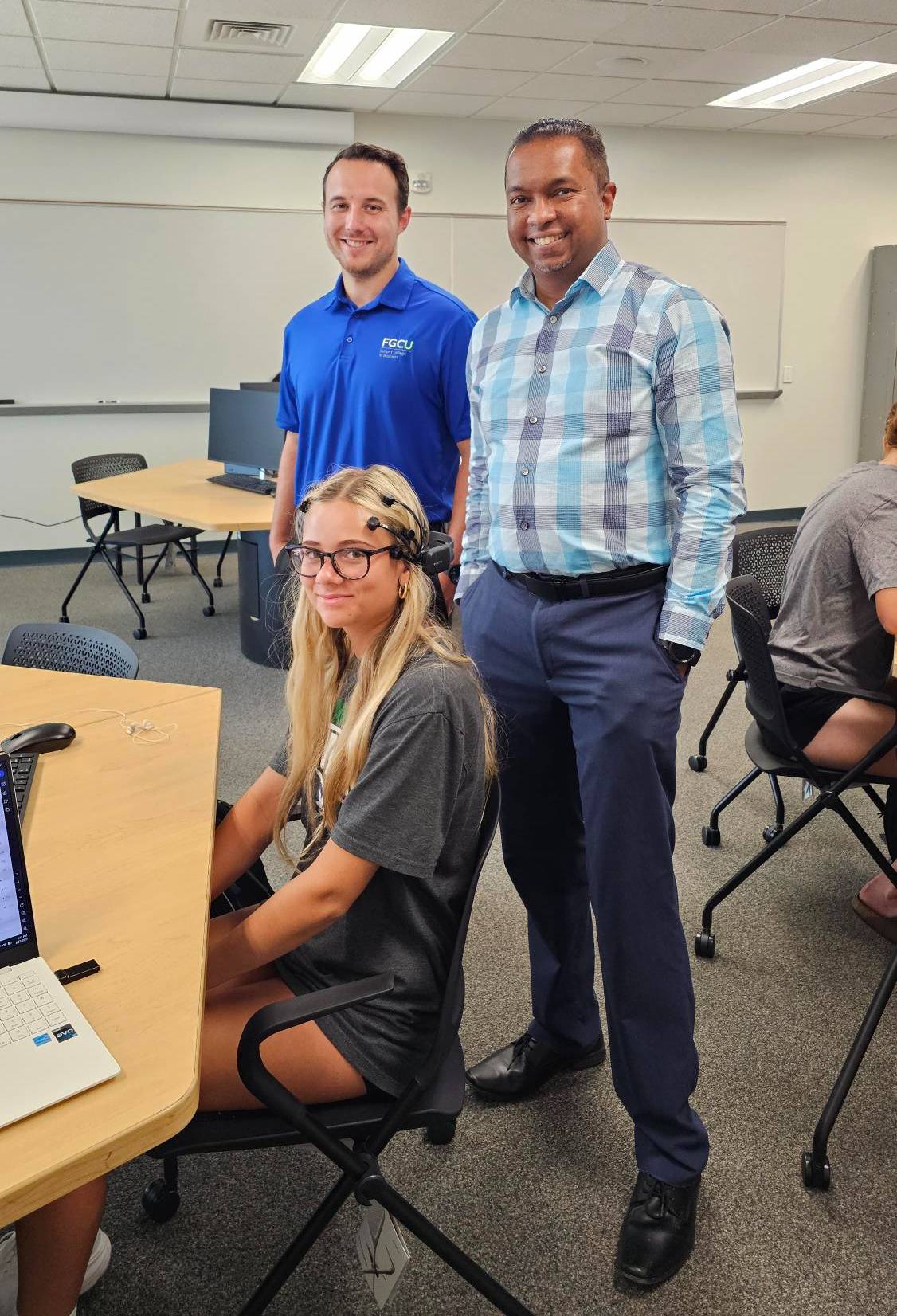 Dr. Shawn Granitto, left, and Dr. Kalana Malimage, right, of the Department of Accounting, work with a student, center, using brainwave technology during a research session.