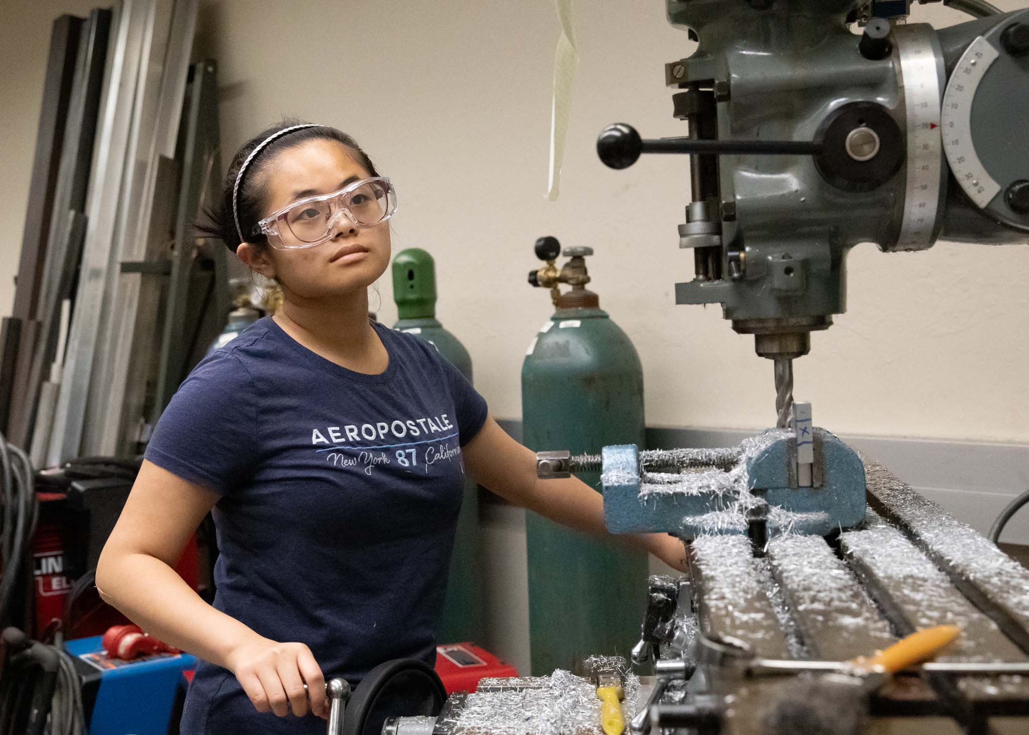 Student uses a large drill in the machine lab.