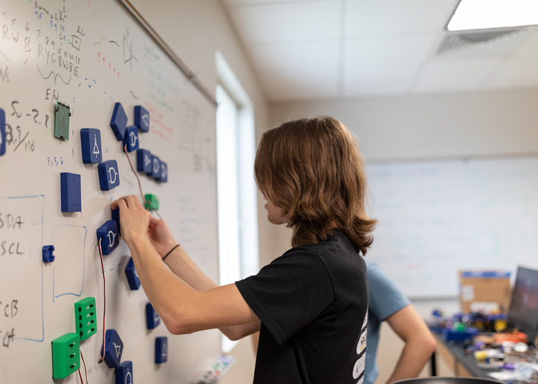 A student uses magnets on a white board 