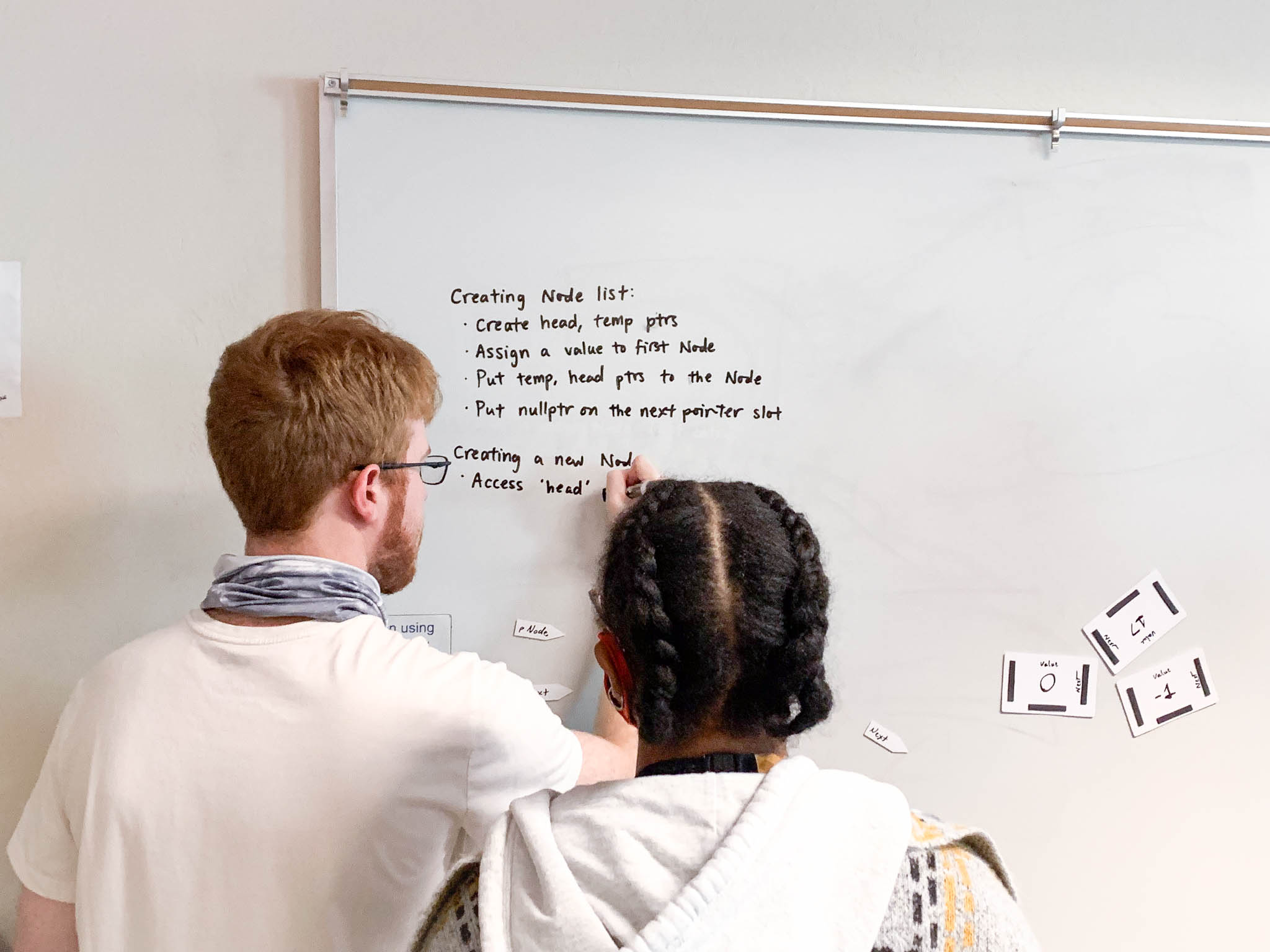 Two students work on a problem on a whiteboard