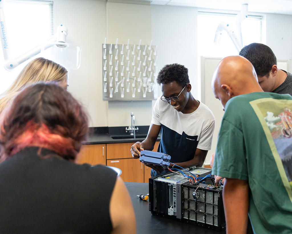 Software engineering students take apart a PC during a hardware lab.