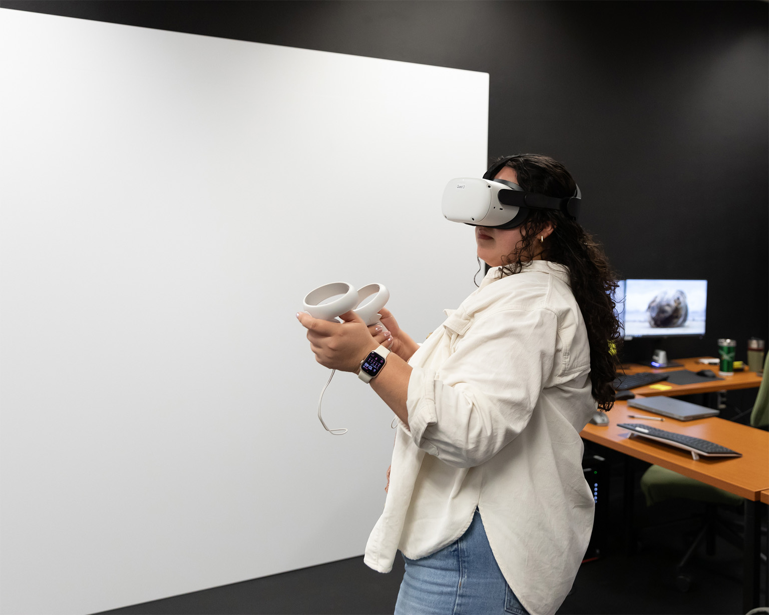 A student uses a Virtual Reality headset and controllers.