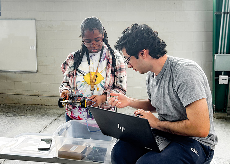 Two software engineering students work on a robot car