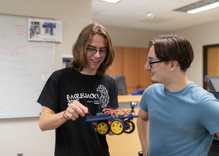 Two students work on a small robot together