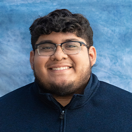 Headshot of a student in a navy blue shirt and glasses.