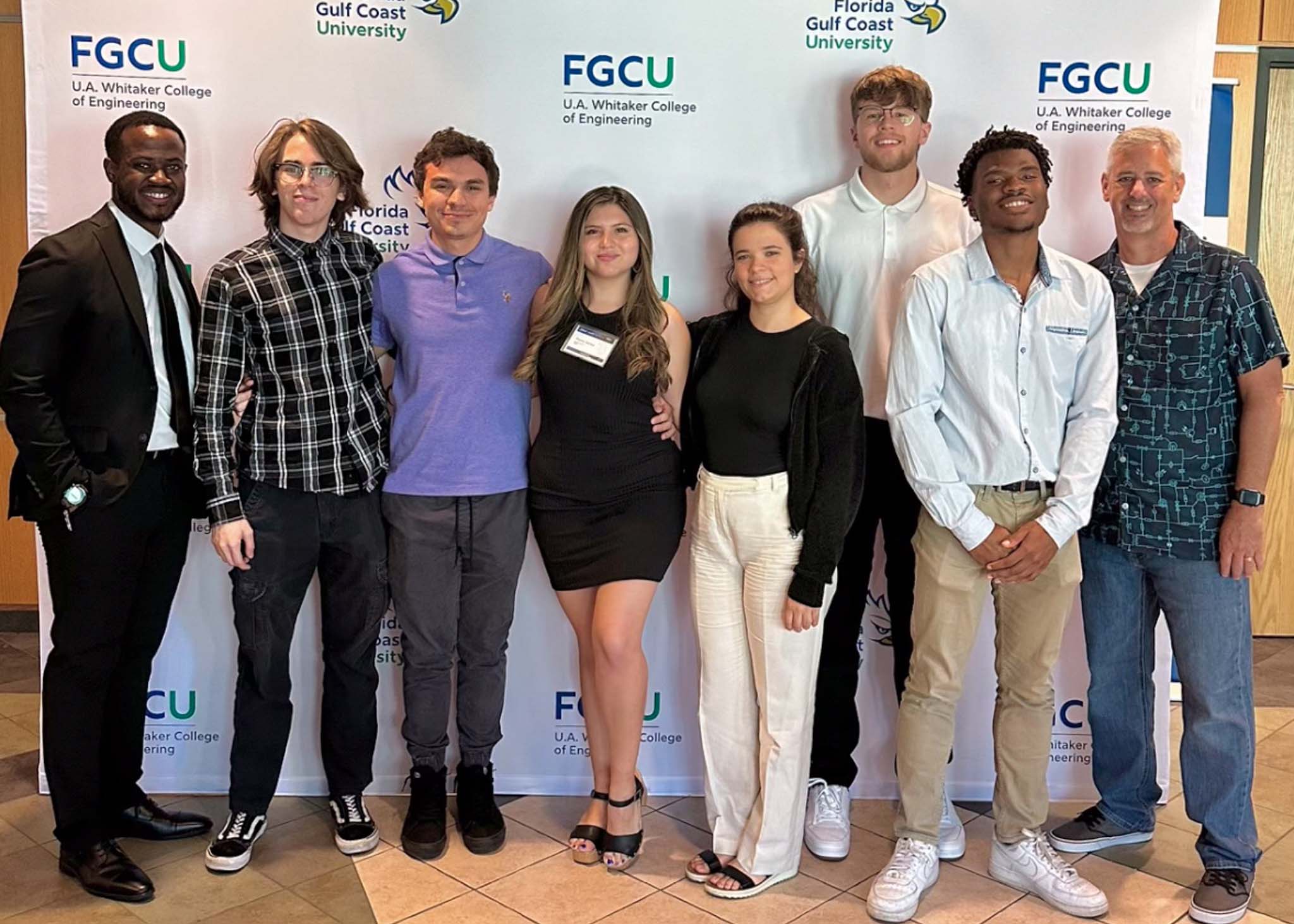 Group of students standing in front of a white backdrop with the FGCU logo