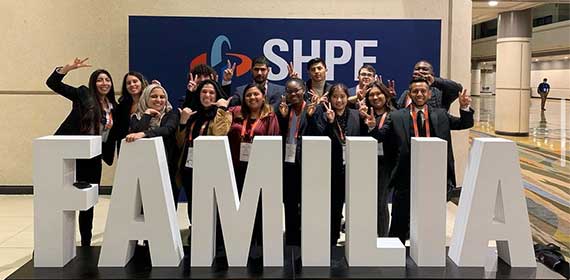 Large group of students standing behind large white letters that spell "familia"
