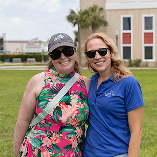Two faculty members stand together outside a building