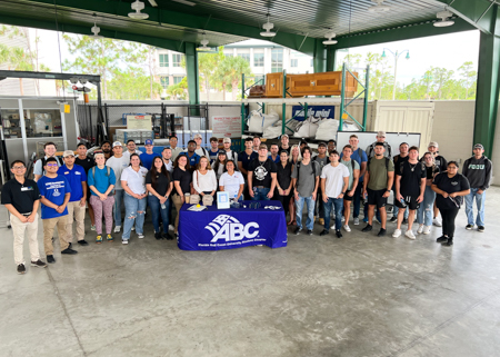 A large group of people stand by a table that says ABC