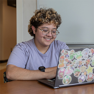 A student with curly hair looks at their laptop