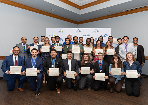 A group of professors and inductees stand with their certificates