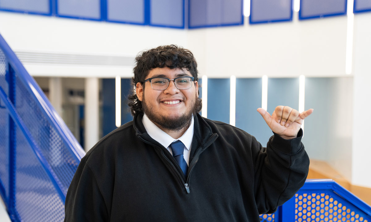 Alexis smiles while doing the "wings-up" hand sign