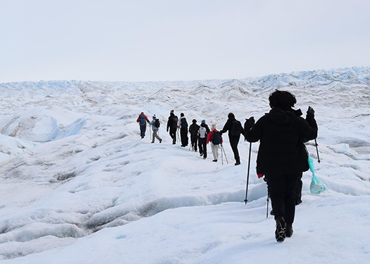 People in heavy coats hike through ice.
