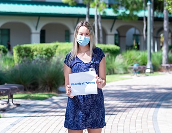 Hannah Lee holds sign stating "#LeeHealthStrong"