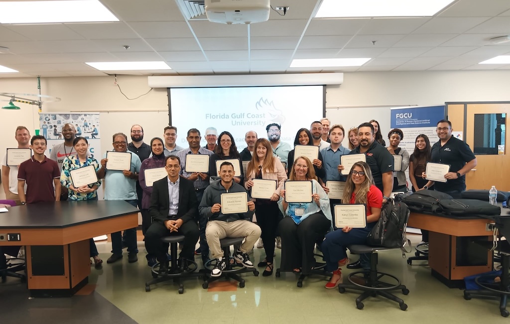 A group of FGCU employees in a classroom hold up their certificates of completion
