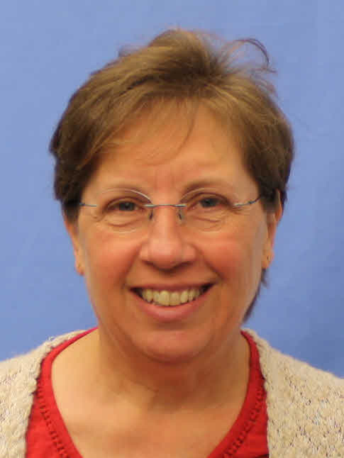 Headshot of a FGCU employee. The employee has short brown hair, is wearing reading glasses, a red shirt, and a beige cardigan.
