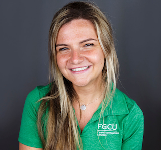 Headshot of Bryn Goldsmith with long hair, smiling and facing the camera. She is wearing a green polo shirt with the text 'FGCU Career Development Services.' The background is plain and dark.