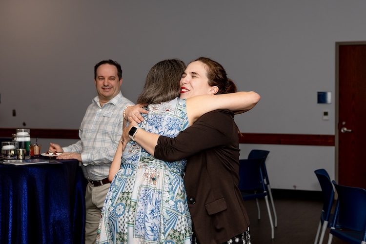 Two women hug each other.