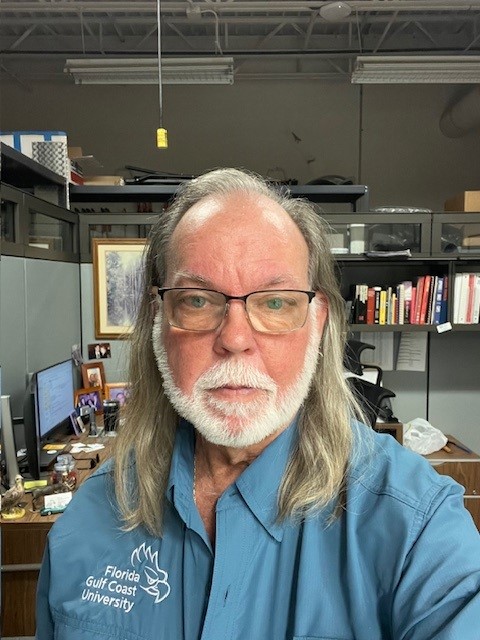 Headshot of James Lee. He has blond hair and is wearing reading glasses and a blue shirt. 