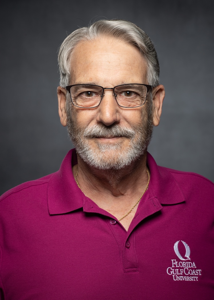 Headshot of Paul Billard, telecommunications technician II with Information Technology Services. He retired Jan. 10. Paul is wearing a magenta polo shirt and reading glasses.  