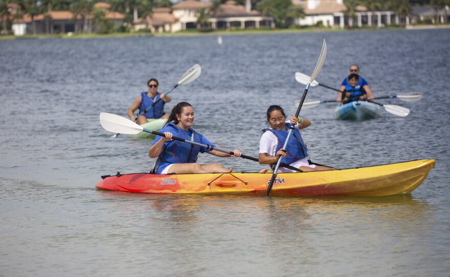 Image of girls kayaking at the waterfont sing adaptive kayaking equipment 