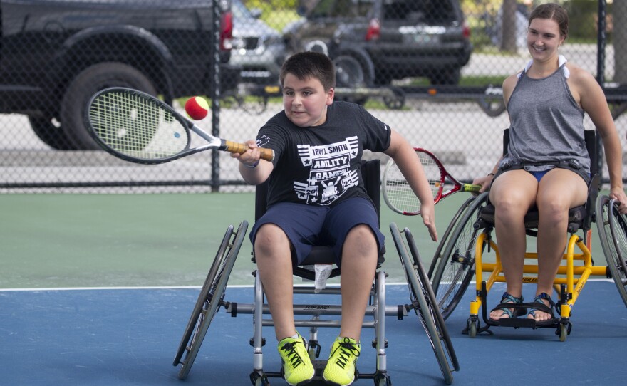 A child in a wheelchair playing wheelchair tennis