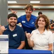 Image of FGCU GIDDI Staff at table gesturing wings up at service learning fair