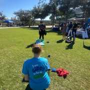 Image of FGCU GIDDI Staff at Soaring for Service where a game of cornhole acts as advocacy for blind adaption