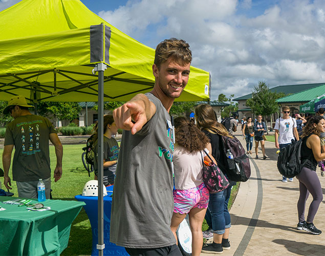 Man smiling and pointing at camera on campus